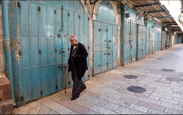 Un palestino camina entre las tiendas, que permanecen cerradas, del mercado de la Ciudad Vieja de Jerusalén. EFE/A. Sultan