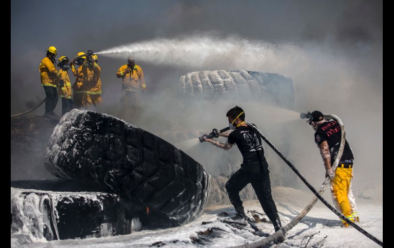 Bomberos apagan unas enormes llantas de tractor que fueron incendiadas con una anotrcha desde Gaza en la frontera en una nueva jornada de tensión entre israelíes y palestinos. AP  / T. Abayov