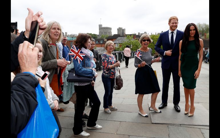 Turistas se toman fotos con figuras de cera del príncipe Enrique y la actriz Meghan Markle cerca del castillo de Windor, en la ciudad inglesa del mismo nombre. La pareja se casará el próximo 19 de mayo. AP/A. Grant