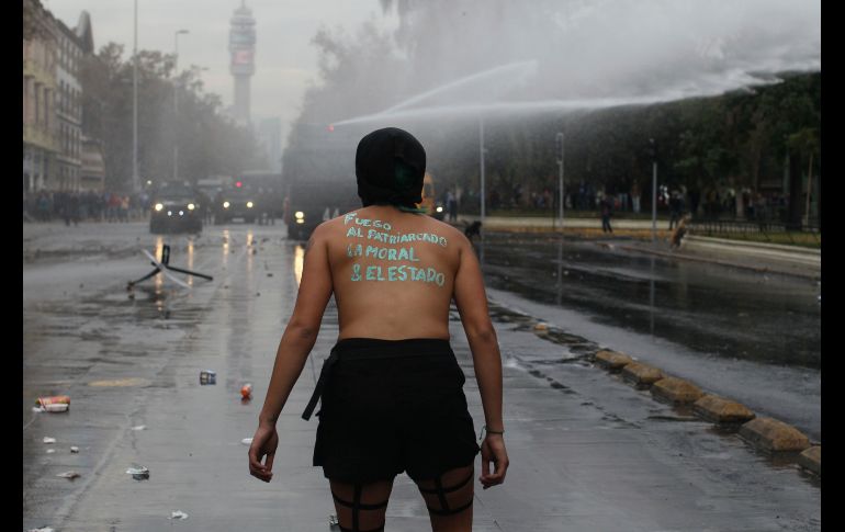Una mujer enfrenta vehículos policiales que arrojan agua. AP/L. Hidalgo