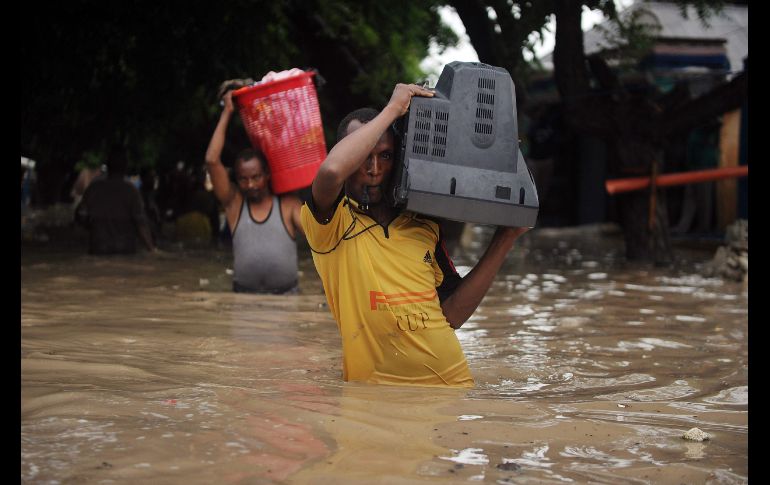 Un hombre carga una televisión luego de una inundación en Mogadiscio, Somalia, debido a una fuerte tormenta. AFP/M. Abdiwahab
