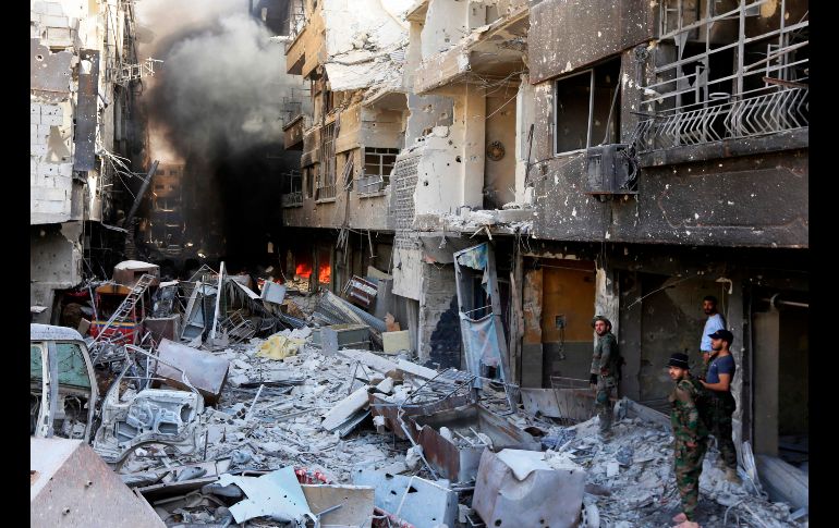 Fuerzas del gobierno sirio caminan por una calle destruida en las afueras de Damasco, luego del anuncio de que el ejército sirio retomó el control total de la provincia de Damasco, por primera vez desde 2012, tras derrotar al Estado Islámico. AFP/L. Beshara