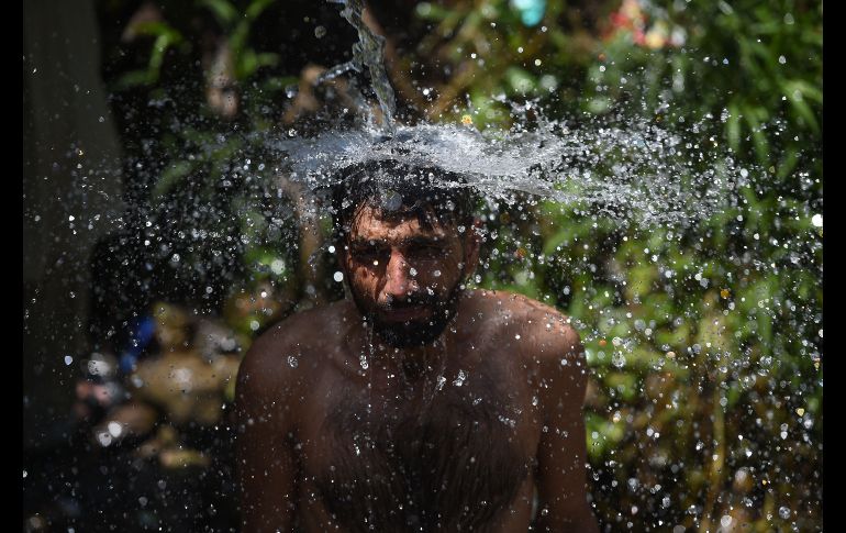 En un día caluroso en Islamabad, Pakistán, un hombre se baña bajo una pipa de agua. AFP/F. Naeem