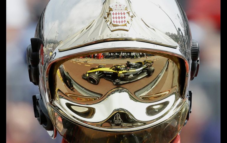 El auto del piloto Nico Hulkenberg, de Renault, se refleja en el casco de un bombero durante la primera sesión de prácticas para el Gran Premio de Fórmula 1 en Mónaco. AP/C. Paris