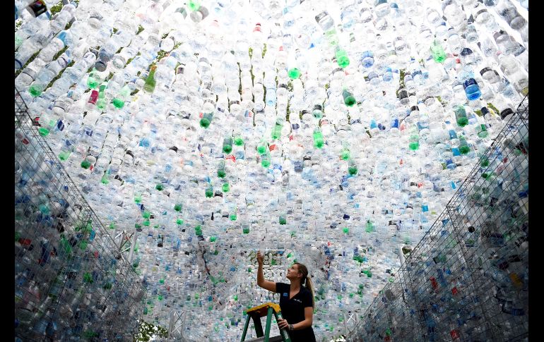 Una empleada coloca una botella de plástico en la escultura 