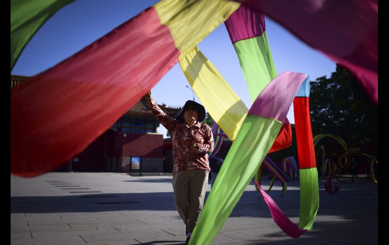 Una mujer baila con un listón en un parque de Pekín, China. AFP/W. Zhao