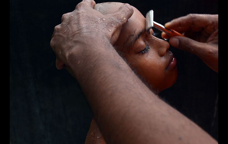 A un joven le rasuran las cejas durante una ceremonia al entrar como monje budista en Eheliyagoda, Sri Lanka. AFP/L. Wanniarachchi