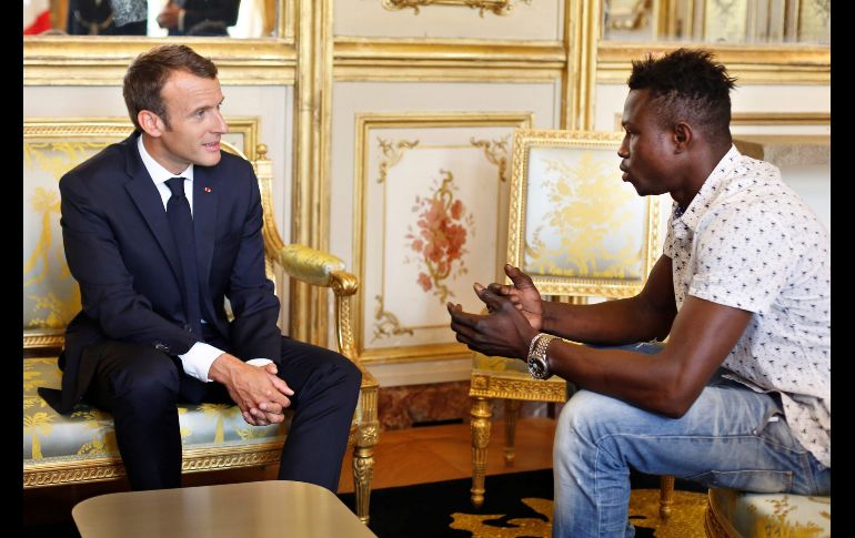 El presidente francés Emmanuel Macron (i) recibe al malí Mamoudou Gassama en el Palacio del Elíseo en París. Al migrante irregular se le concederá la ciudadanía francesa luego de darse da conocer que escaló la fachada de un edificio para salvar a un niño que colgaba de un quinto piso. AP/T. Camus