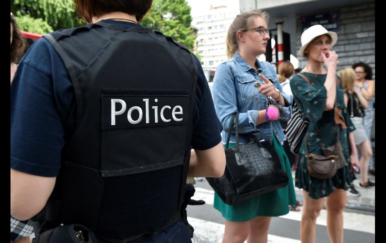 Un policía hablan con padres de niños en una escuela cercana al lugar de la agresión. AFP/J. Thys