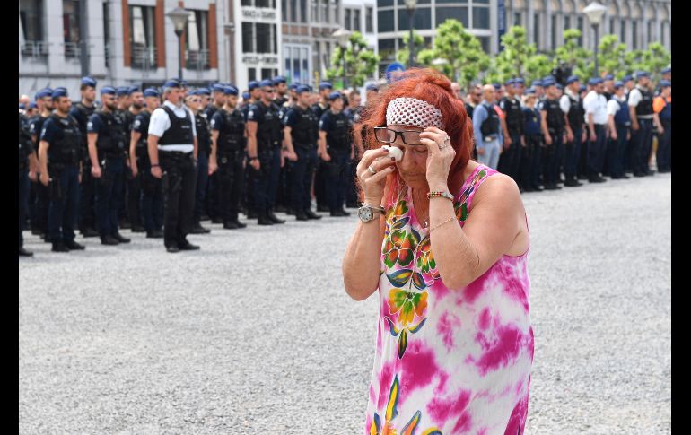 Una mujer llora mientras pasa junto a policías en Lieja, Bélgica, que guardan un momento de silencio por las víctimas del ataque de ayer por parte de un presunto terrorista, que dejó tres víctimas mortales. AP/G. Vanden Wijngaert