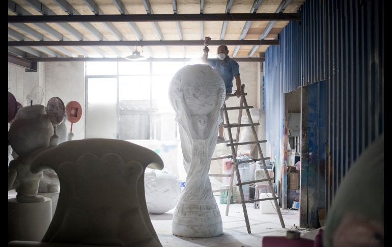 Un trabajador rocía espray en una réplica gigante del trofeo de la Copa del Mundo de la FIFA en una fábrica de Shanghái, China. AFP/J. Eisele