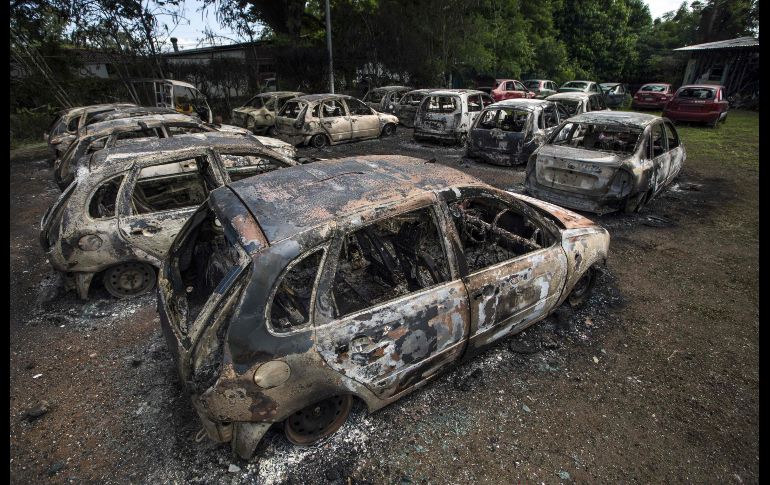 Autos quemados se ven afuera de una sede del banco oficialista Caruna, en Managua, Nicaragua. Grupos opositores al gobierno quemaron el sitio. AFP/I. Ocon