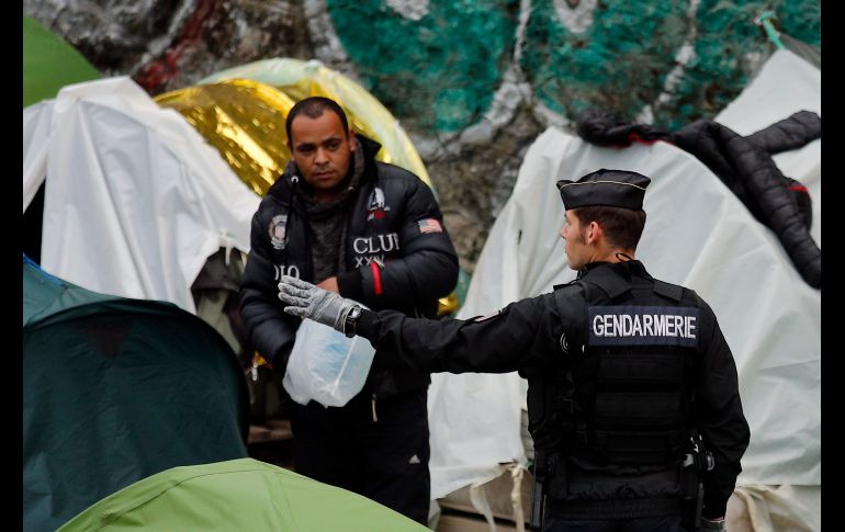 Un gendarme hace señas a un migrante, durante el desalojo de un campamento de migrantes junto al canal Saint Martin, en París. AP/F. Mori