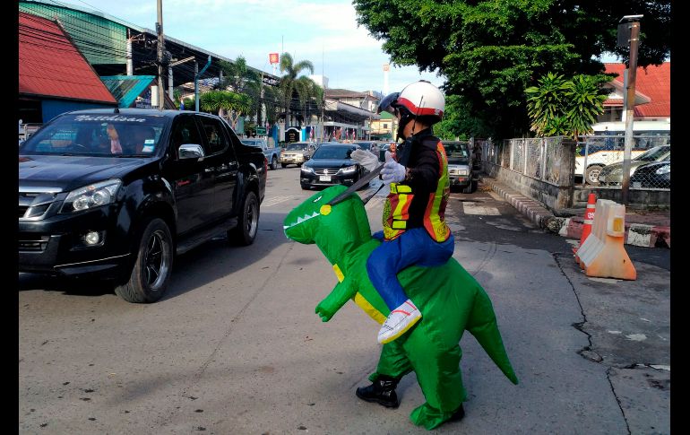El policía Tanit Bussabong dirige el tráfico con un disfraz de un dinosaurio, afuera de una escuela en Nakhon Nayok, Tailandia. Bussabong tiene unos 20 disfraces que usa para su trabajo afuera del kínder. AFP/S. Boitano
