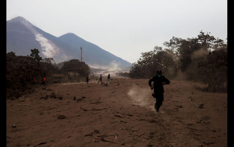 Un policía corre por un deslizamiento de fluido del volcán en San Miguel Los Lotes.