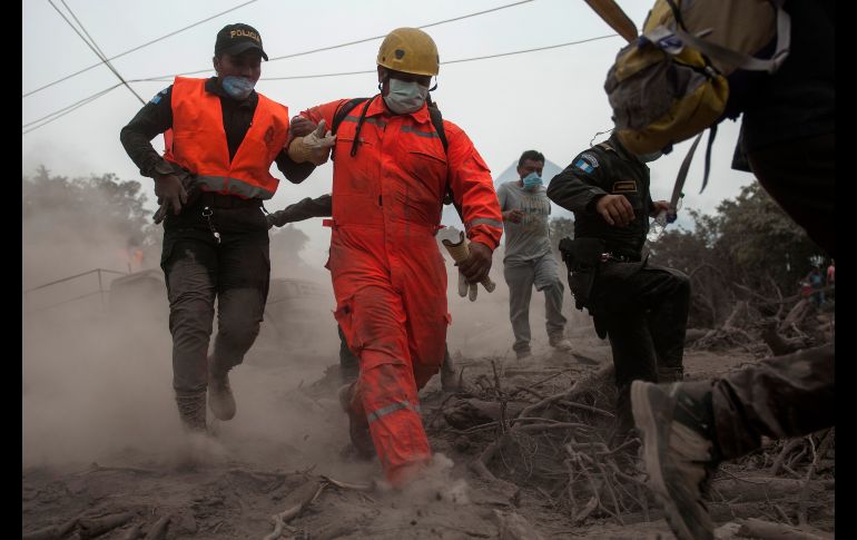 Bomberos y policías que realizaban un operativo de búsqueda en Escuintla, Guatemala, corren tras un deslizamiento del volcán de Fuego. La cifra de muertos a causa de la erupción del volcán suma 62. AP/O. de Ros