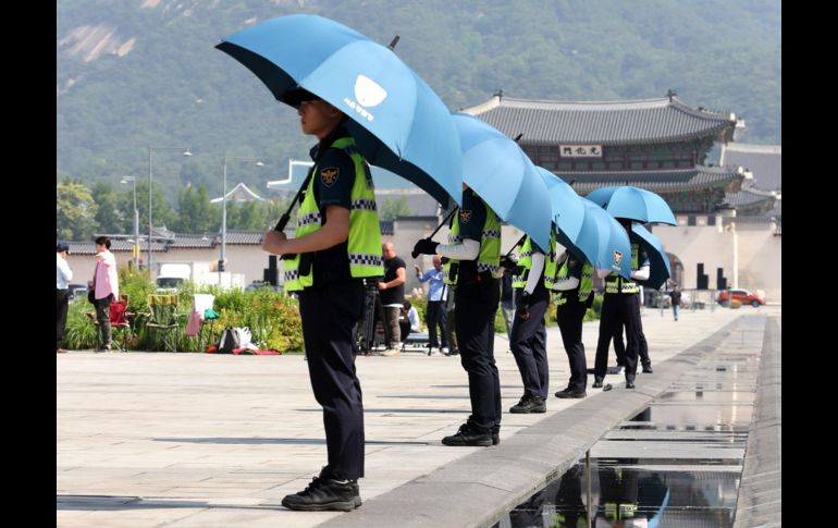 Varios policías usan paraguas mientras trabajan bajo un intenso calor en la plaza Gwanghwamun en Seúl, Corea del Sur. EFE/ Yonhap