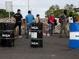 Varios jóvenes portan escudos artesanales mientras mantienen cortada la carretera a Masaya. EFE/J. Torres