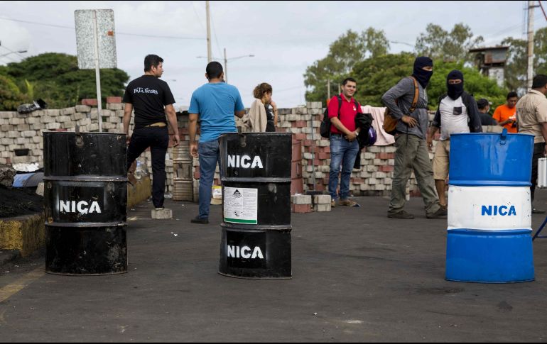 Varios jóvenes portan escudos artesanales mientras mantienen cortada la carretera a Masaya. EFE/J. Torres