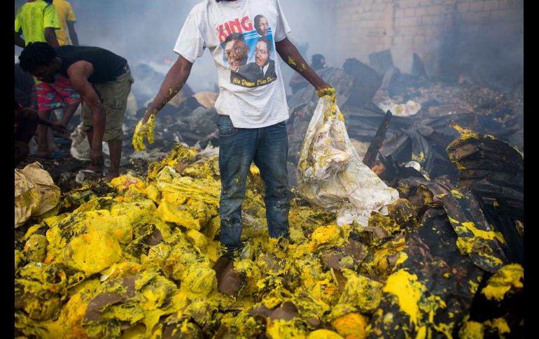 Un vendedor camina en una montaña de restos de mostaza mientras trata de salvar abarrotes luego del incendio que consumió el principal mercado de Puerto Príncipe, Haití. AP / D. Nalio