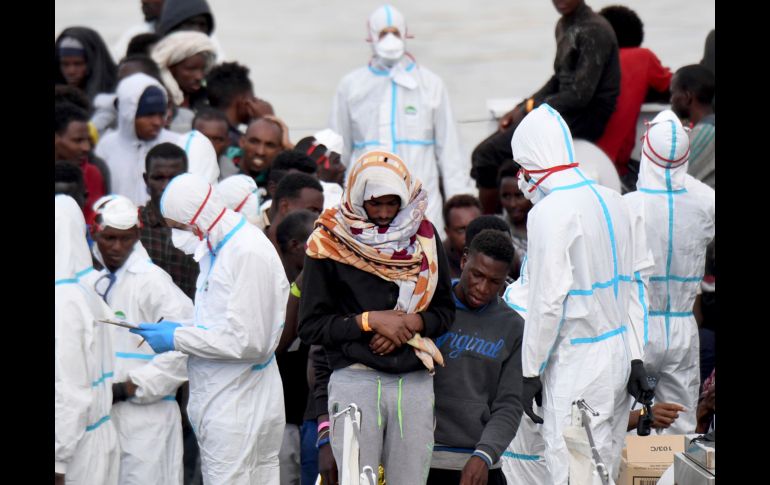 Inmigrantes desembarcan del barco de la Guardia Costera italiana 