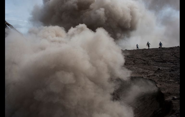 Personas caminan entre una nube de cenizas por el trabajo de maquinaria pesada San Miguel Los Lotes, Guatemala, durante la búsqueda de desaparecidos tras la erupción del volcán. AP/R. Abd