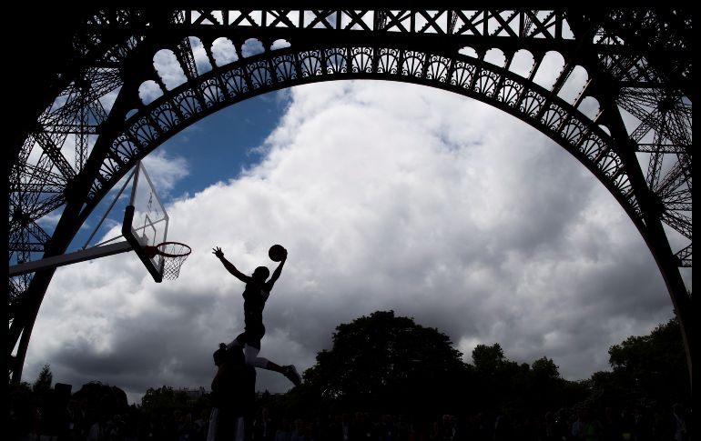 Varias personas juegan al baloncesto debajo de la Torre Eiffel, durante la visita de los miembros de la Comisión de Coordinación del Comité Olímpico Internacional a París. La ciudad busca la sede de los Juegos de 2024. EFE/ I. Langsdon