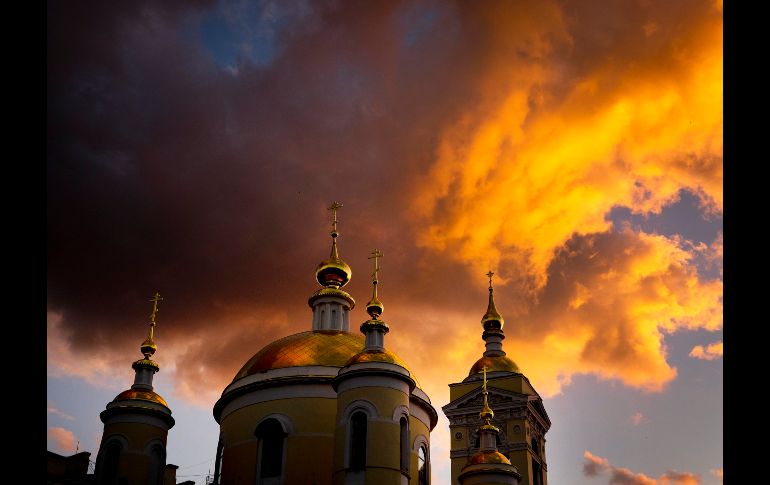 Nubes se iluminan durante la puesta de Sol sobre un templo en Podolsk, Rusia. AP/M. Probst