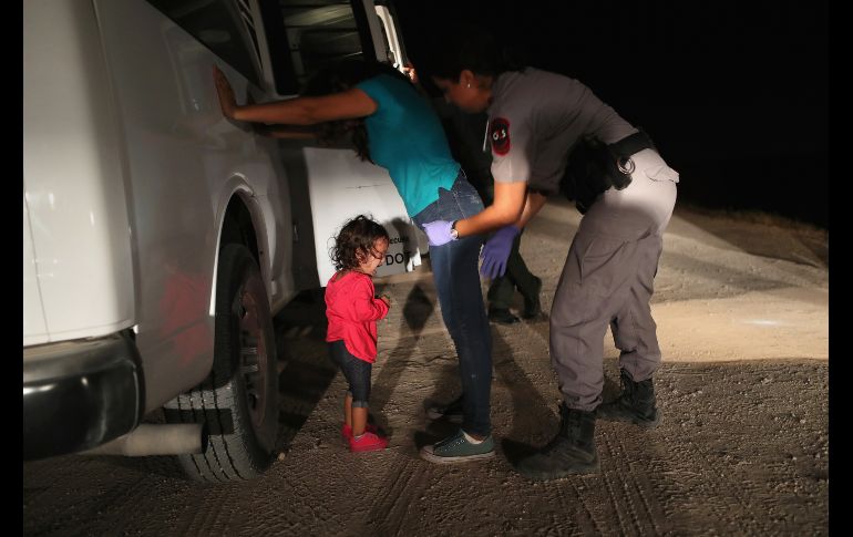 La niña comenzó a llorar cuando su madre la puso en el suelo, pues los agentes le pidieron que la soltara. AFP/J. Moore