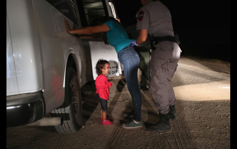 La niña comenzó a llorar cuando su madre la puso en el suelo, pues los agentes le pidieron que la soltara. AFP/J. Moore