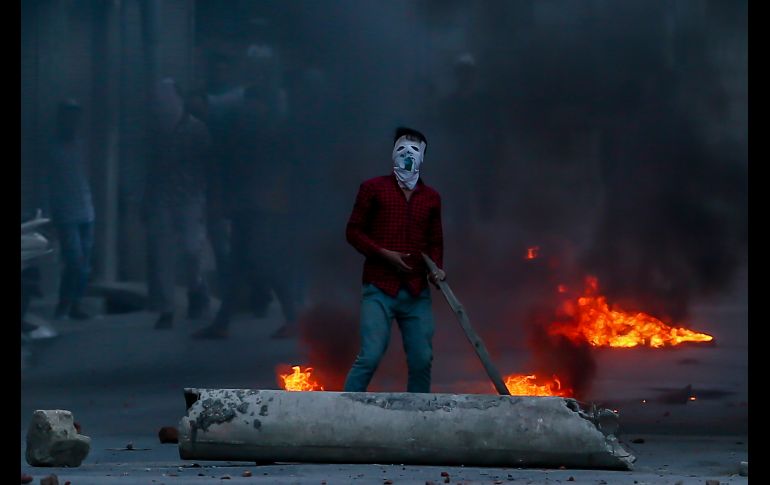 Un cachemir se manifiesta en Srinagar, India, mientras policías arrojan gas lacrimógeno. Separatistas cachemires llamaron a una huelga en protesta por las muertes de civiles y un peridista. AP/D. Yasin