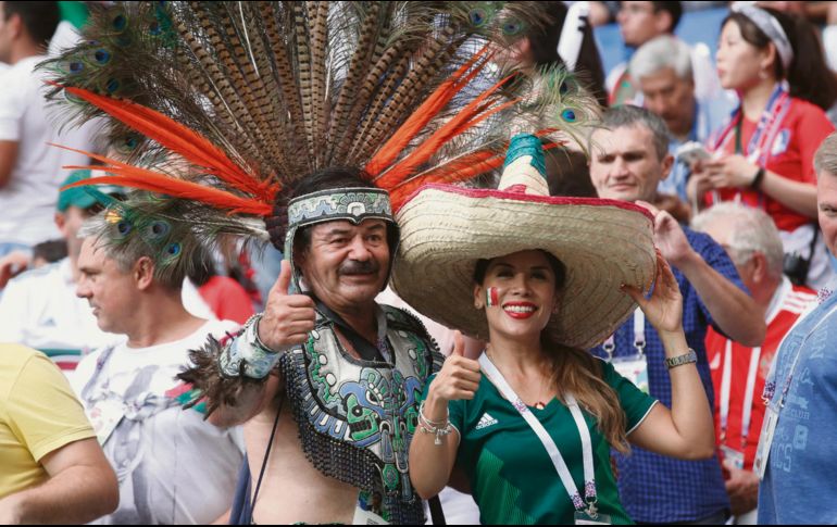 Emplumado. Un mexicano vestido de azteca posa con otra aficionada tricolor en medio de fanáticos de Corea del Sur en Rostov. AFP