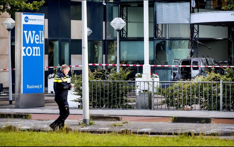 Un oficial de la policía pasa delante de la furgoneta que se empotró contra la sede del diario De Telegraaf en Amsterdam. EFE/K. Van Weel