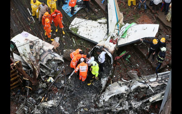 Personal de emergencias trabaja en el lugar donde se estrelló una avioneta en Bombay, India. Al menos cinco personas, entre ellas un peatón, murieron hoy tras la caída contra un edificio en construcción. EFE/D. Solanki