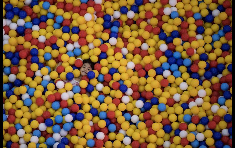 Una niña se esconde en una alberca llena con pelotas en un centro comercial en Manila, Filipinas. AFP/N. Celis
