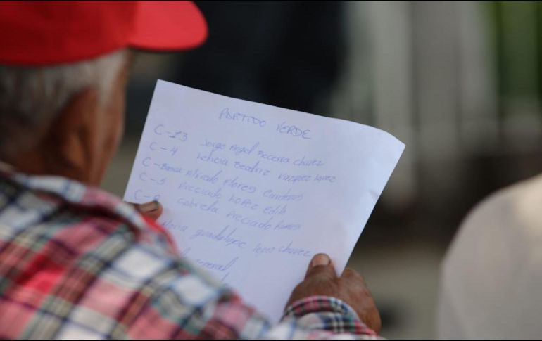 Dentro de la escuela, dos hombres con gorras rojas y playeras blancas, sentados en una de las jardineras, anotaban a mano nombres de ciudadanos EL INFORMADOR/ F. Jaramillo