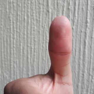 Lleva su marcador a la casilla; la tinta en su dedo apenas se ve