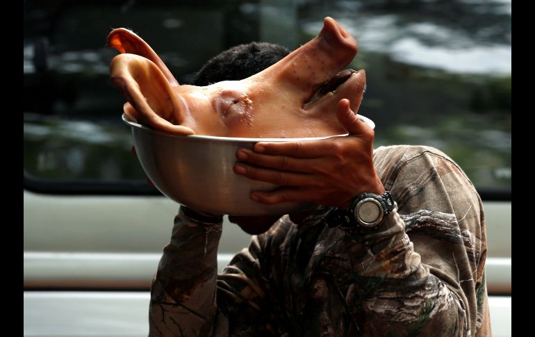Un soldado de la Armada tailandesa lleva una cabeza de cerdo como ofrenda a los guardianes y espíritus celestiales mientras continúan las labores de rescate de los 12 niños y su entrenador atrapados en una cueva en el parque de Khun Nam Nang Non, en Tailandia. EFE/ R. Yongrit