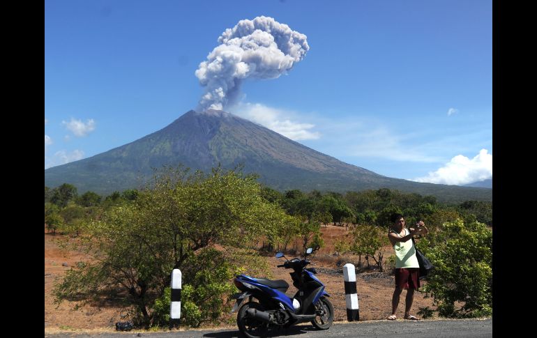 Un turista toma una foto del volcán Agung, en la isla indonesia de Bali, mientras se eleva una columna de ceniza. AFP/S. Tumbelaka