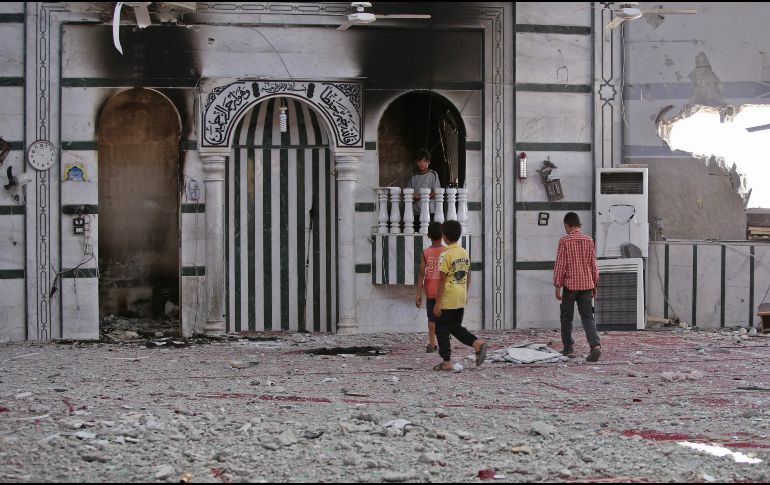 Varios ninos observan una mezquita afectada por los recientes bombardeos. AFP/Y. Karwashan
