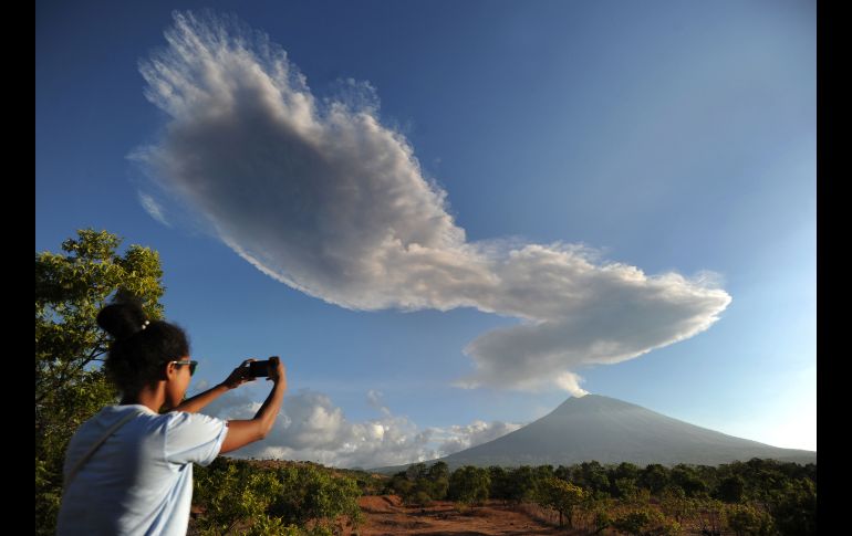 Una mujer fotografía el volcán Agung desde Kubu, en Indonesia. El volcán ha estado lanzando columnas de ceniza de dos mil metros y provocado el cierre temporal del aeropuerto cercano. AFP/S. Tumbelaka