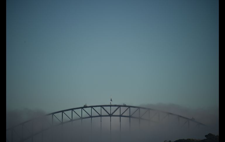Neblina cubre el puente de la Bahía de Sídney, en Australia. Aviones y embarcaciones suspendieron viajes debido al fenómeno  registrado en la mañana. AFP/P. Parks