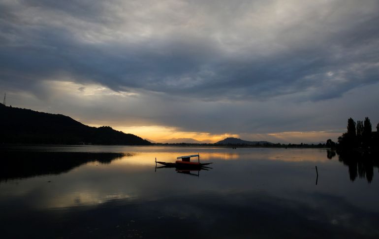Un barco flota en las aguas del lago Dal durante la puesta de sol, en Srinagar, la capital de verano de la Cachemira india. EFE/ F. Khan