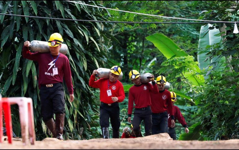 Miembros de los servicios de rescate cargan con botellas de oxígeno mientras continúan las labores de rescate. EFE / R. Yongrit