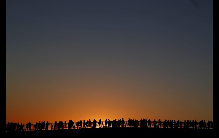 Personas observan el atardecer desde un puente después de que las autoridades alertaran de la próxima llegada del tifón 