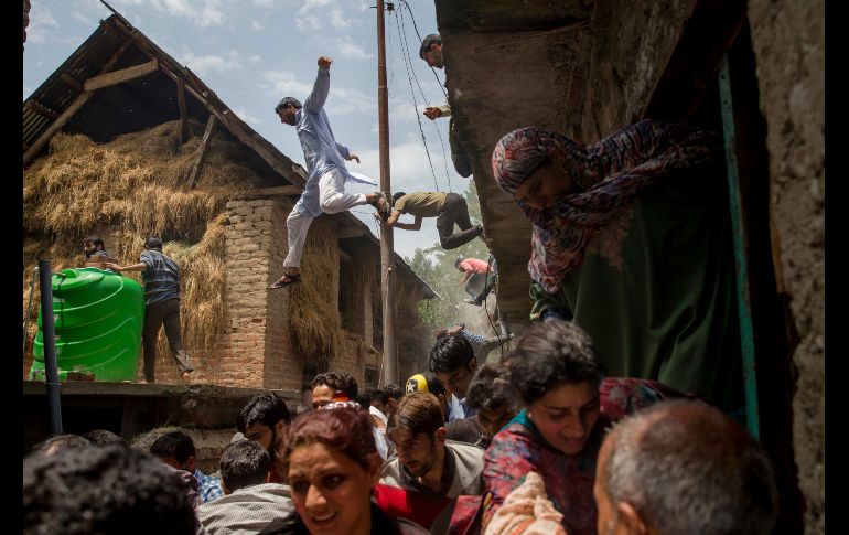 Cachemires que inspeccionan una casa dañada durante un enfrentamiento en Kundalan, India, huyen tras rumores del regreso de militares indios. AP/D. Yasin