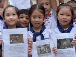 Escolares muestran fotos y dibujos de los socorristas afuera del hospital donde se recuperan los chicos rescatados. AFP/T. Chhin