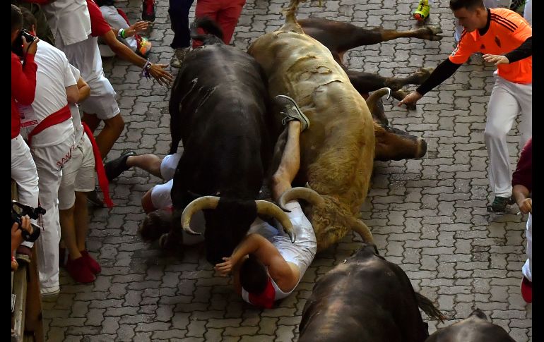 Asistentes al Festival de San Fermín caen al paso de los toros, en el quinto encierro de este año en Pamplona, España. AP/A. Barrientos