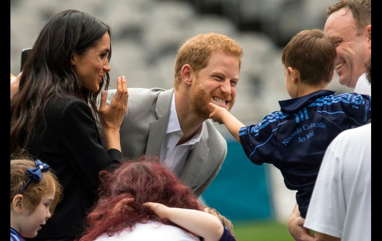 Un niño acaricia al príncipe Enrique, acompañado por su esposa Meghan, en Dublín. La pareja asistió a un evento en su segundo día de visita a la capital irlandesa. AP/D. Lipinski