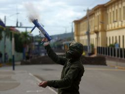 Militante opositor dispara un mortero hechizo. AFP/M. Recinos